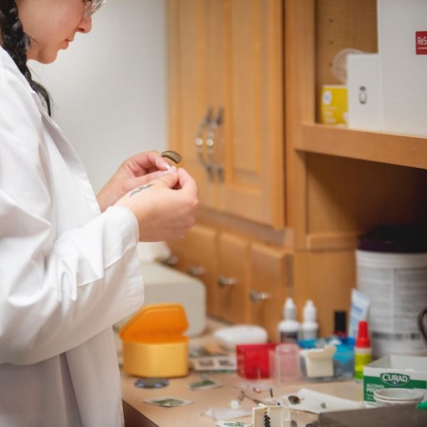 hearing specialist repairing a hearing aid