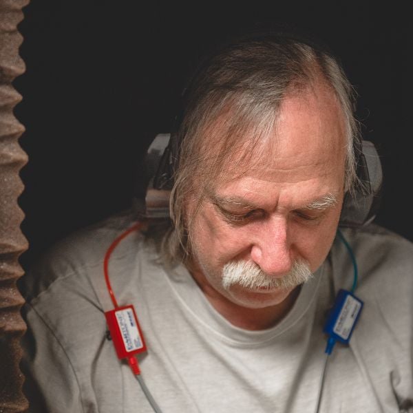 man sitting in a testing booth with headphones on