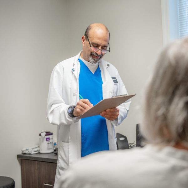 hearing specialist reading a clipboard with a patient