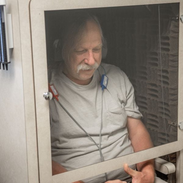 man sitting in a testing booth with headphones on
